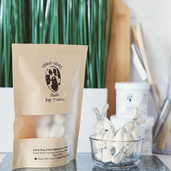 Photo - Freeze-dried frog legs dog treats in branded packaging on a kitchen counter. Natural high-protein pet treats. Montreal, Canada.